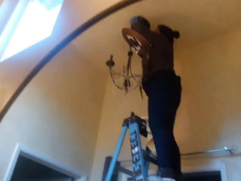Electrician installing a chandelier in a Coon Rapids residence
